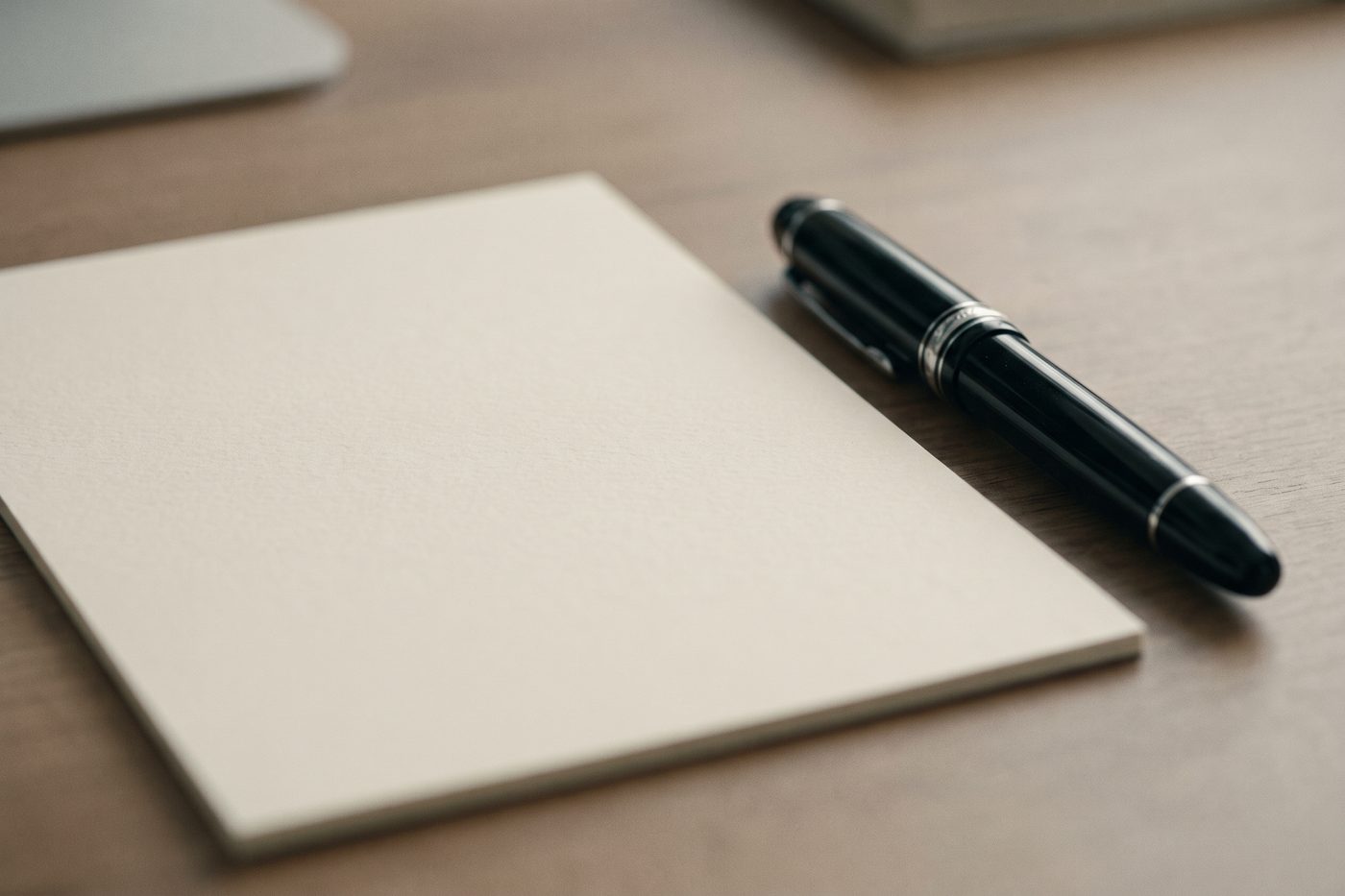 A completely blank cream form on a matte navy desk beside a capped fountain pen, cool overhead light