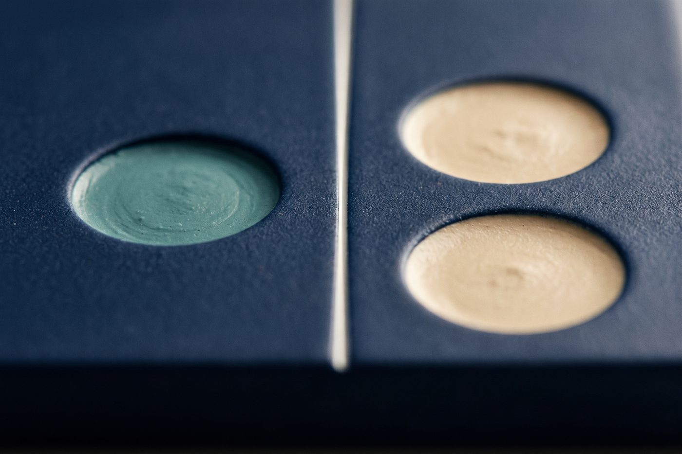 A navy slab with one filled recess on the left and two filled recesses on the right, a bright seam of light running between them