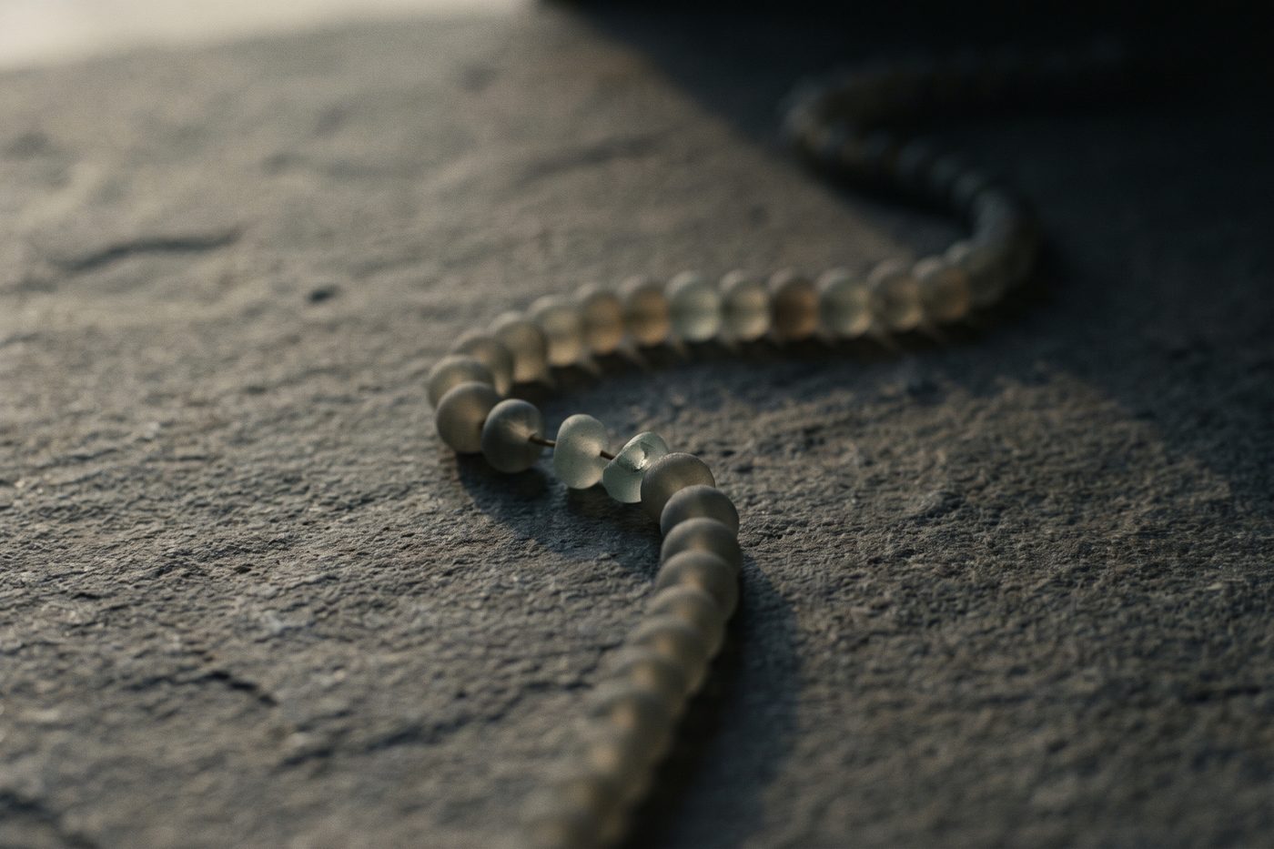 A long chain of frosted beads broken in the middle, the shorter segment sharp in the foreground