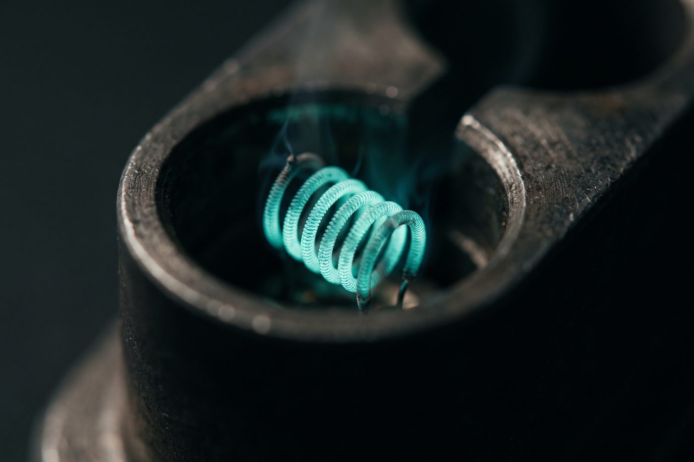 A glowing teal filament burning inside a dark chamber of brushed metal, extreme macro, soft bloom, navy